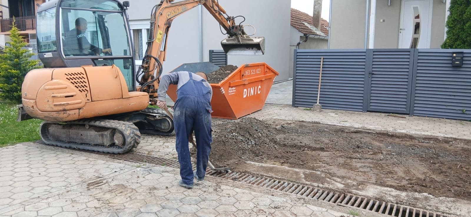 Radnik i bager vrše utovar građevinskog materijala u kontejner u Novom Sadu